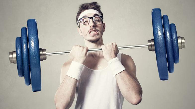 Junger Mann mit Nerdbrille stemmt Langhantel