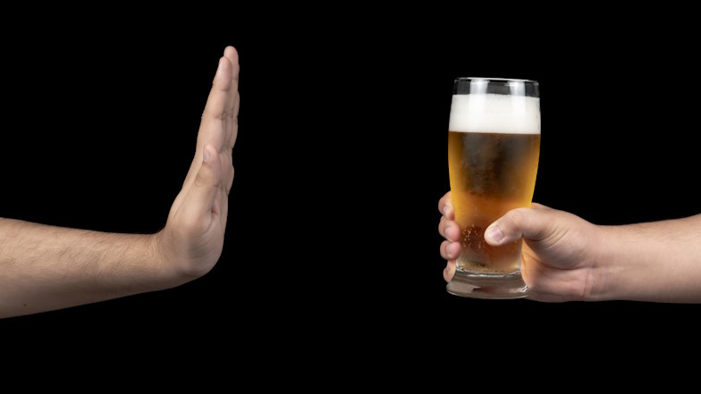 Männliche Hand weist ein angebotenes Glas Bier ab