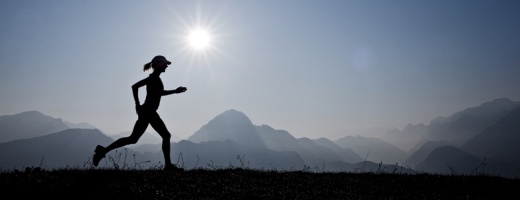 Silhouette einer Joggerin vor einer Bergkulisse mit Gegenlicht